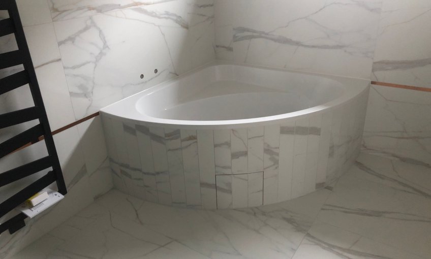 Im Badezimmer wurden die Wände bereits fertig gefliest und die Eckbadewanne eingebaut.  