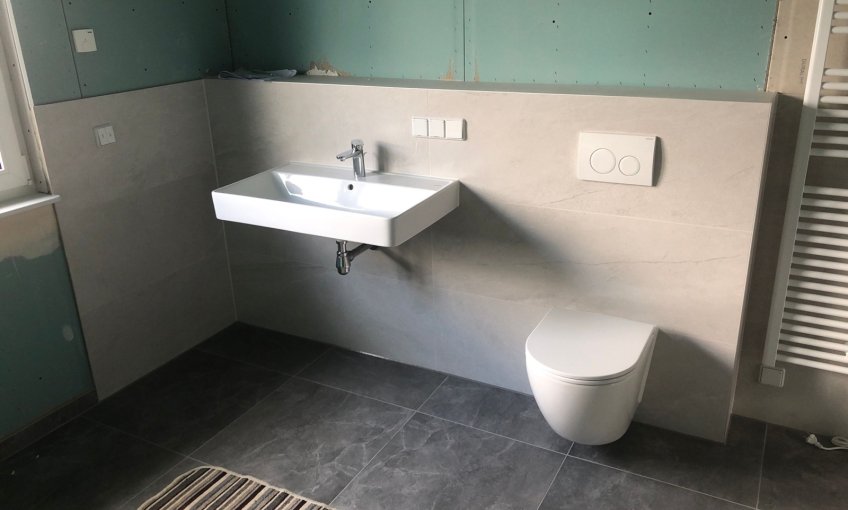 Das Badezimmer wird gefliest. Und die Sanitärobjekte montiert.