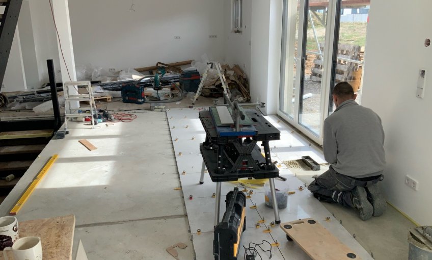 Der Estrich ist jetzt ausgetrocknet und der Fliesenleger kann mit seiner Arbeit beginnen.