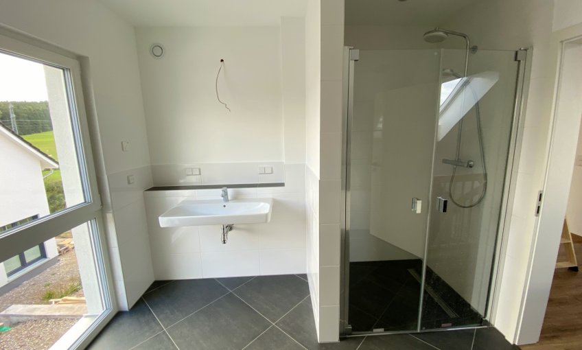 Die bodentiefe Dusche mit einer Glastür ergänzt das Bad zu einer Wellness-Oase.