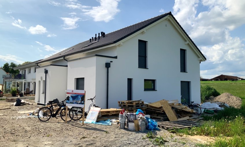 Das Gerüst wurde abgebaut und nun kommt das Haus so richtig zur Geltung. Ein toller Kontrast zum weißen Außenputz ist die dunkle Dachfläche und die farbigen Fenster.